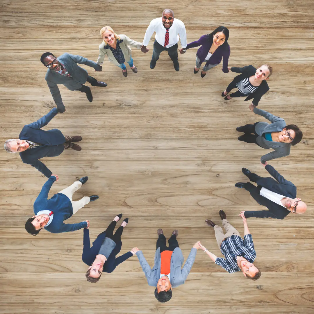 Equipo de trabajo inclusivo tomándose de las manos en una oficina segura y colaborativa