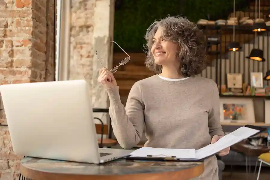 Mujer de más de 40 años sonriendo mientras trabaja en su laptop, simbolizando la reinvención profesional