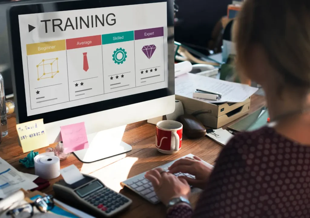 Persona usando una computadora para realizar un curso de formación online, con pantalla que muestra niveles de aprendizaje: principiante, intermedio, avanzado y experto.