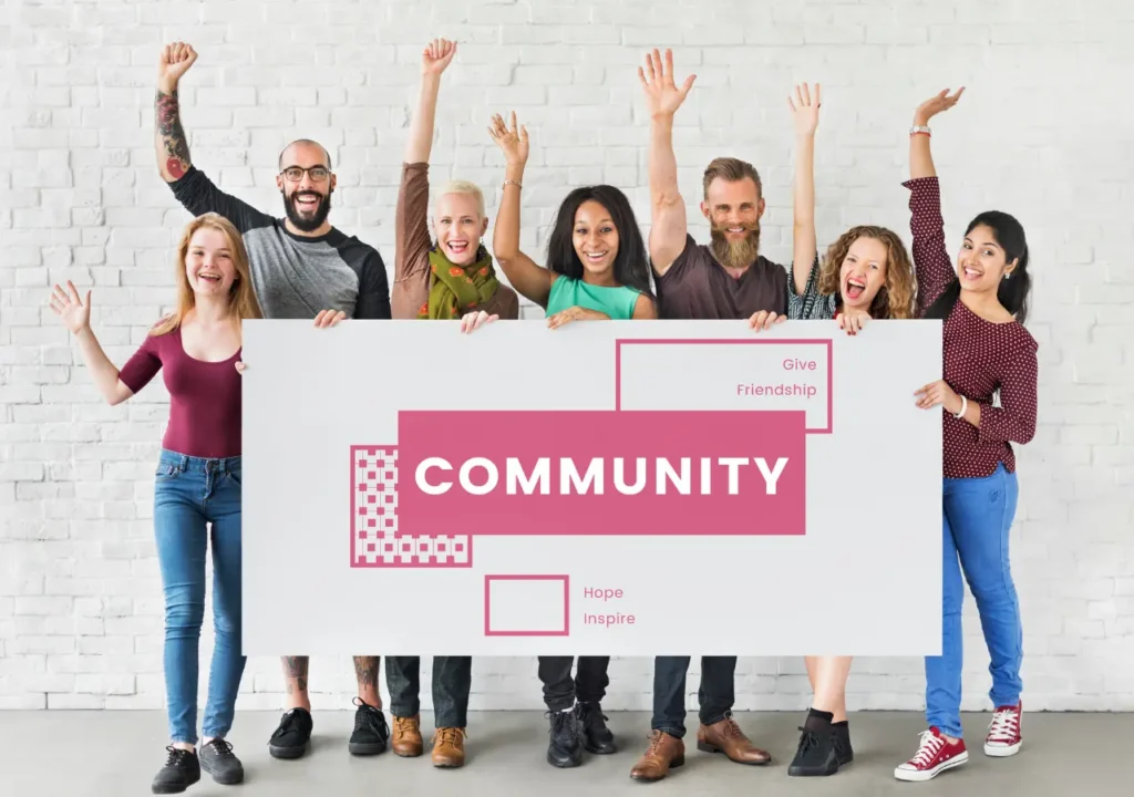 Grupo diverso de personas sonrientes levantando las manos y sosteniendo un cartel con la palabra "Community", simbolizando el valor del voluntariado y los proyectos sociales para mejorar la empleabilidad