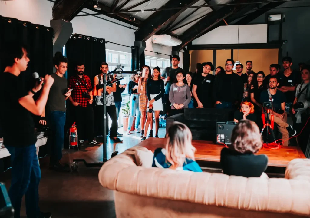 Grupo de jóvenes profesionales asistiendo a un evento de networking, escuchando a un orador y construyendo relaciones en un entorno colaborativo
